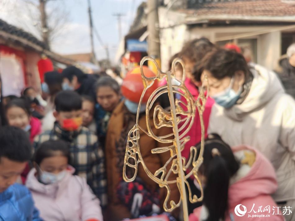 非遗传人用糖画展现冬奥会吉祥物“冰墩墩”，吸引了孩子们前来观赏。人民网记者 王继亮摄