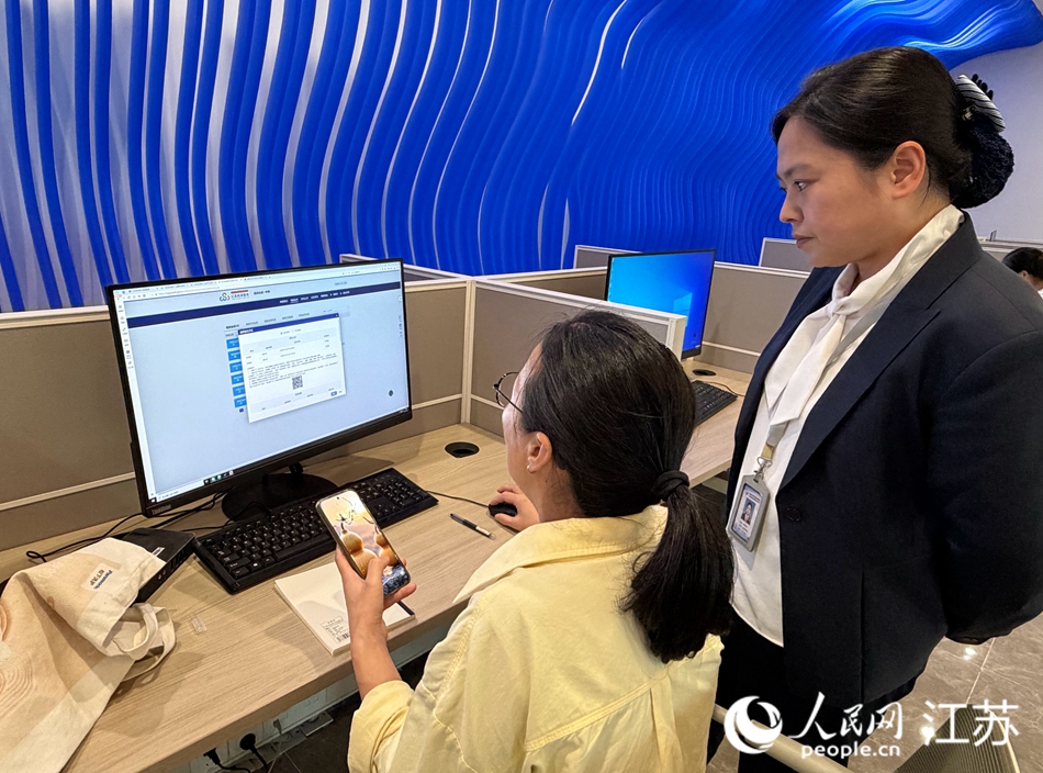 工作人员指导企业办事人员（右）使用“e启办”办理事项。人民网记者 王继亮摄